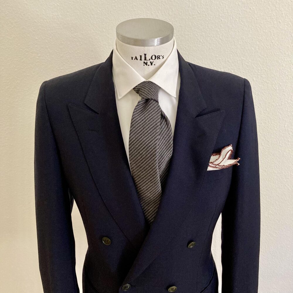 Das Bild zeigt ein Herren Mannequin mit blauem Blazer, weisses Hemd und grauer Krawatte