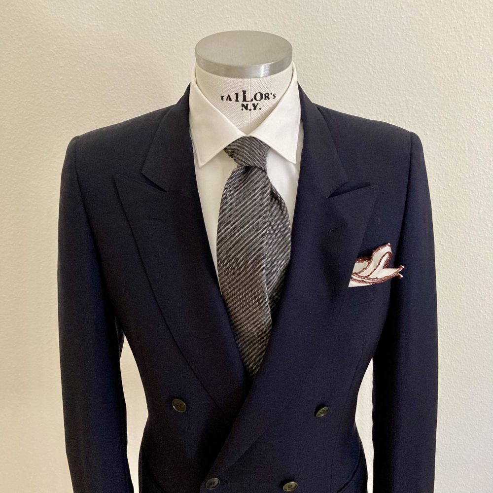 Das Bild zeigt ein Herren Mannequin mit blauem Blazer, weisses Hemd und grauer Krawatte