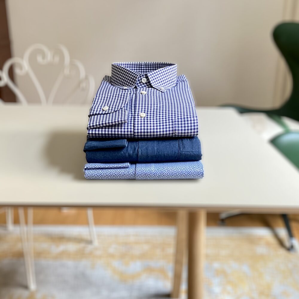 Bequeme Casual Hemden wie Karo, Denim und Print liegen gestapelt auf einem Tisch